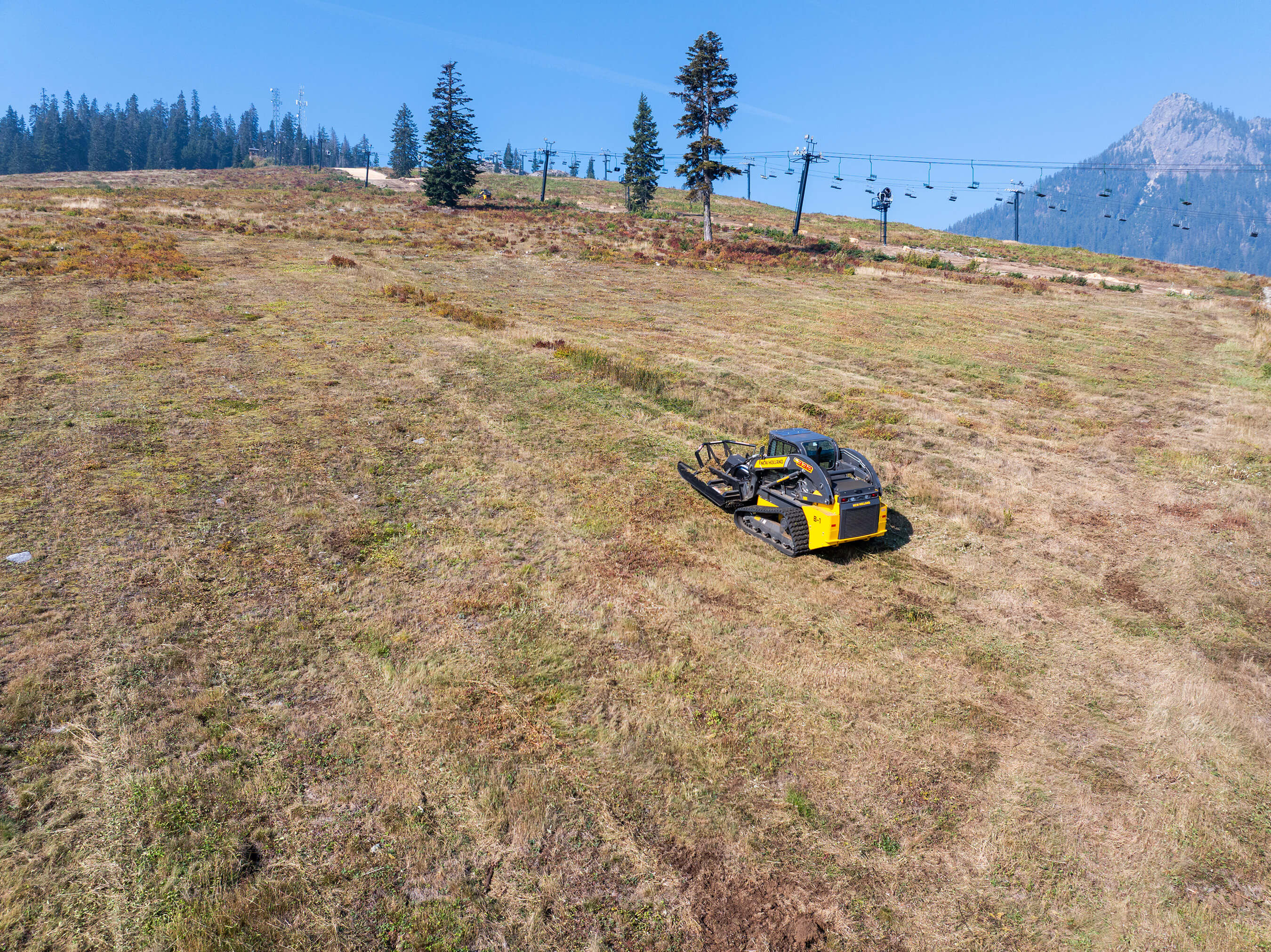 Looking uphill at a brush cutting machine on ski slope at Summit West