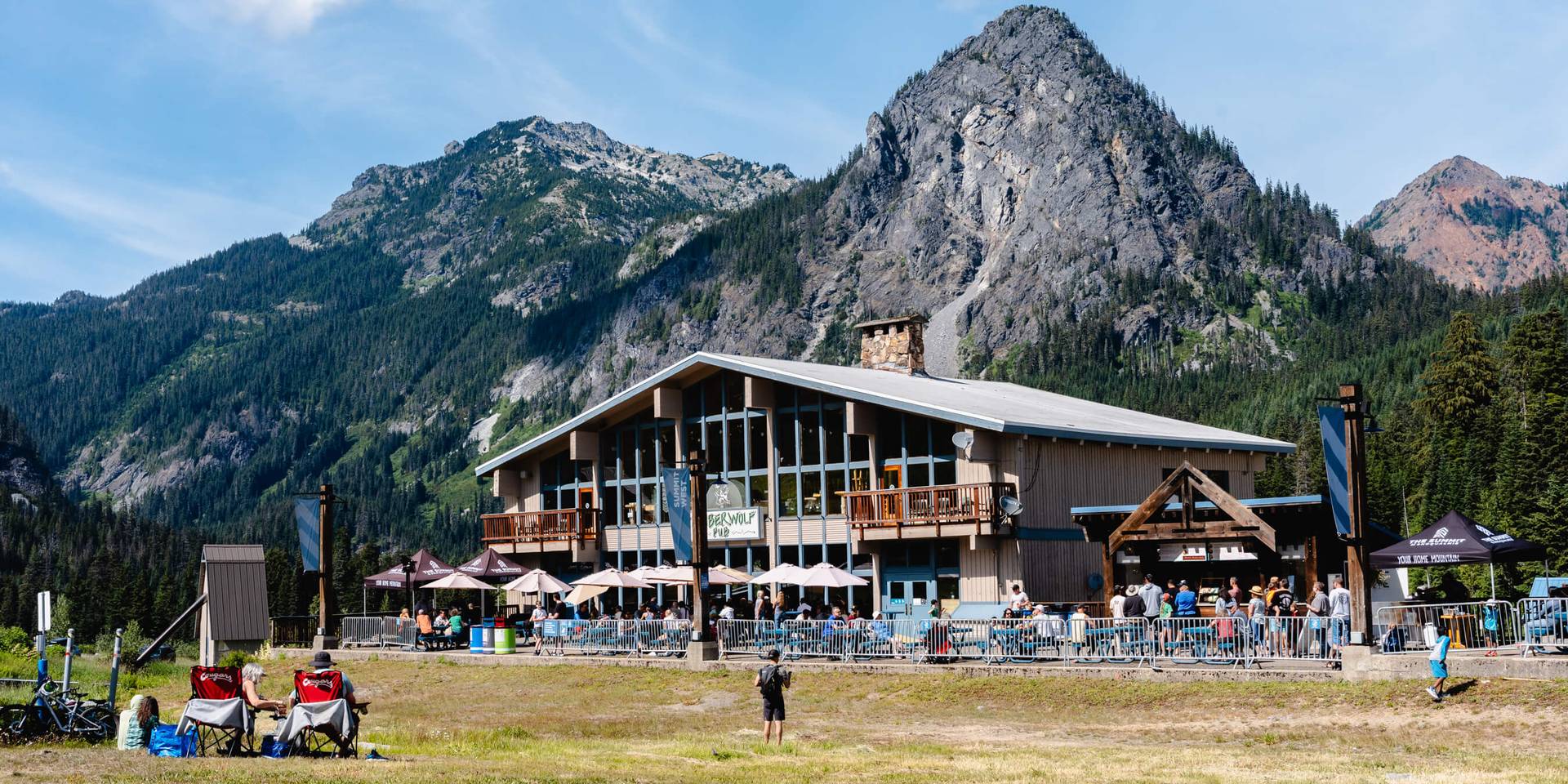 Busy plaza at Summit West on summer day with Guye Peak scenic background