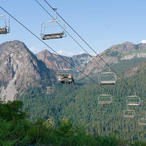scenic chairlift riders downloading with mountains in the background