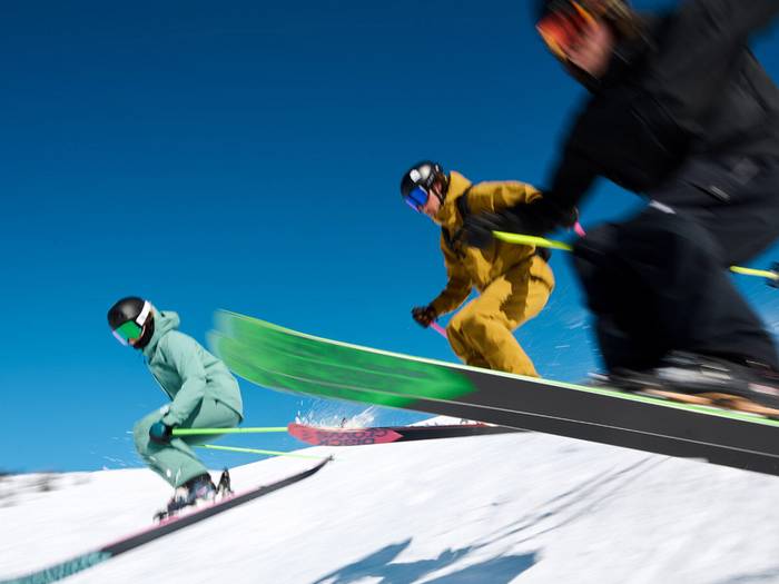 three skiers flying through the air
