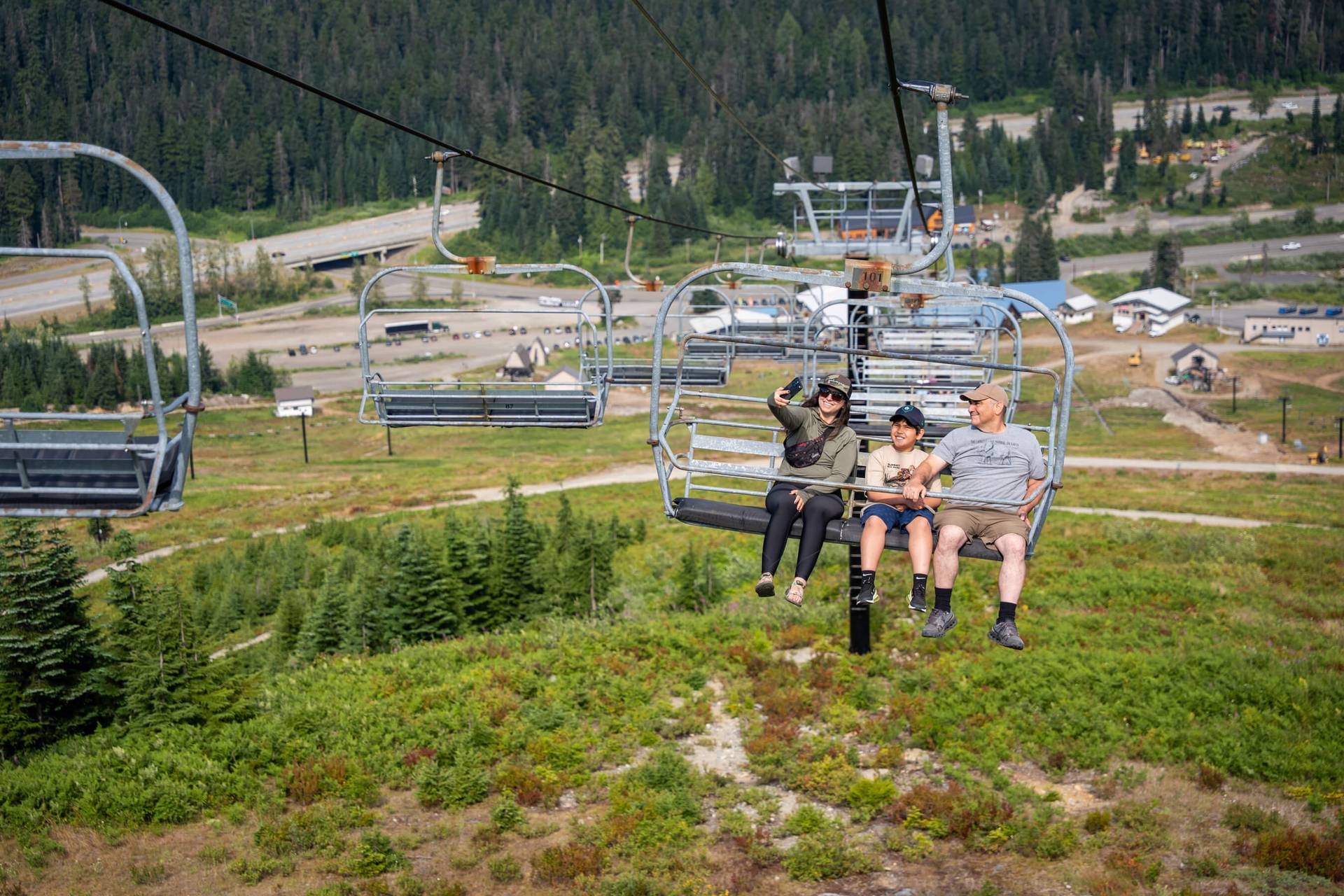 A family of 3 taking a selfie on a scenic chairlift ride