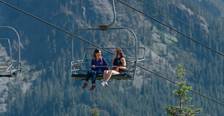 two women sitting on a chairlift enjoying the view