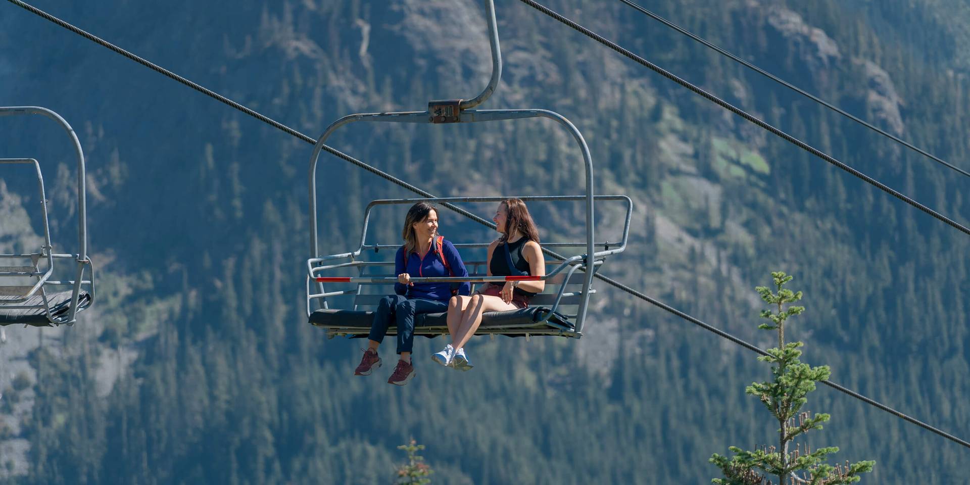 two women sitting on a chairlift enjoying the view
