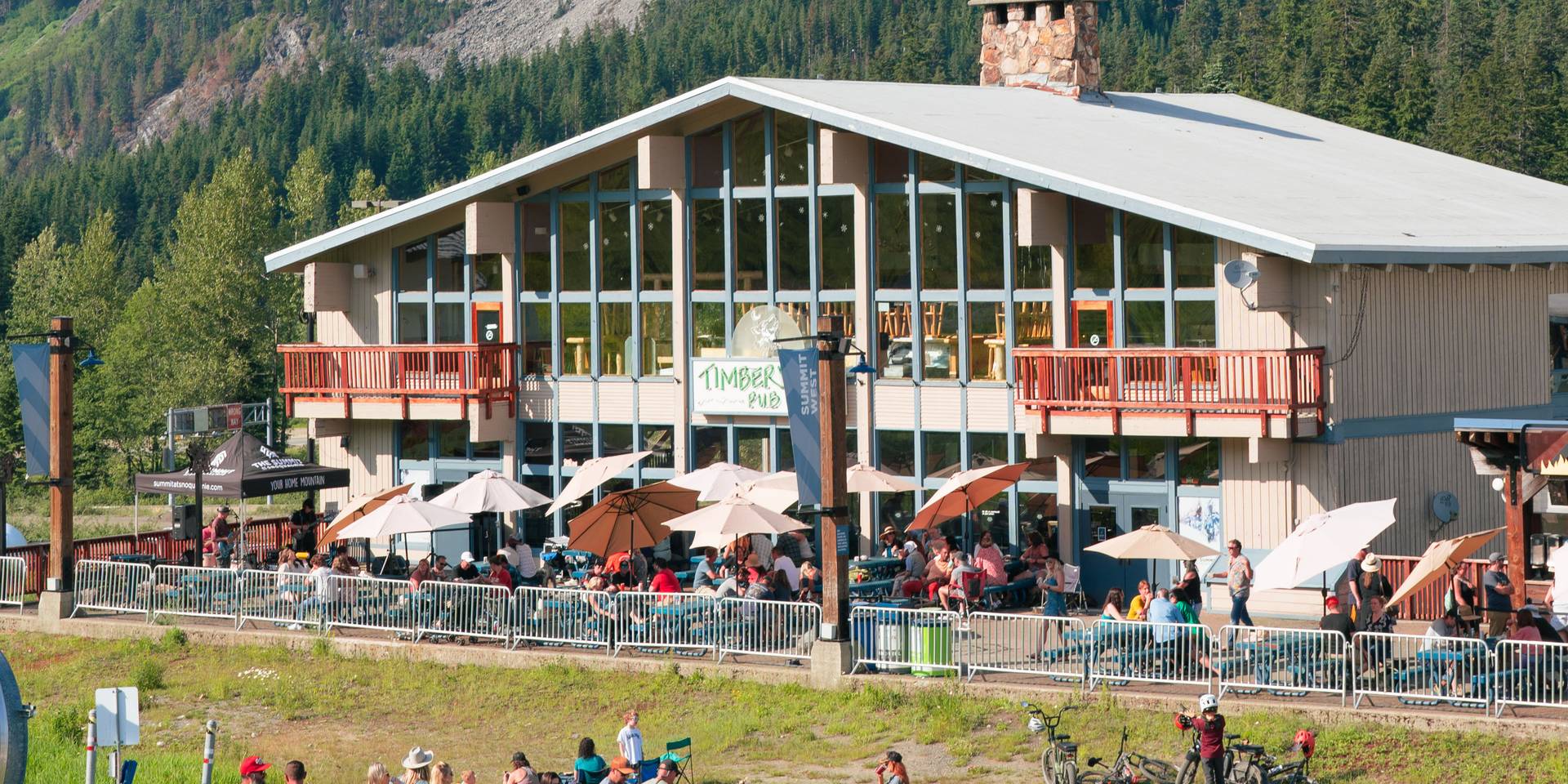 Busy plaza for live music at Summit West on a summer evening with scenic views of Guye Peak