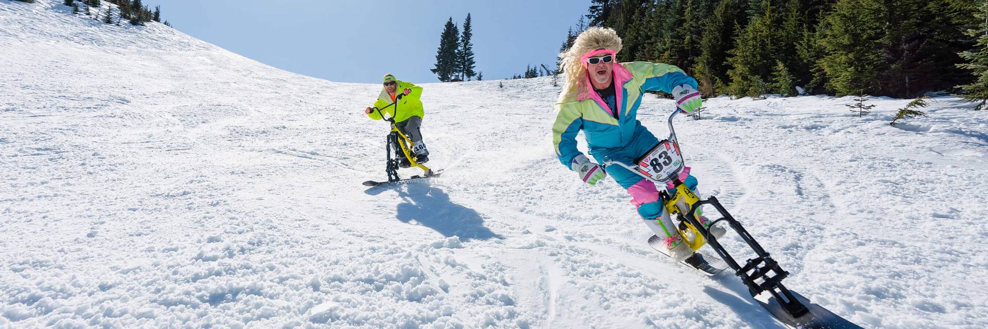 people in neon 80s outfits on snowbikes