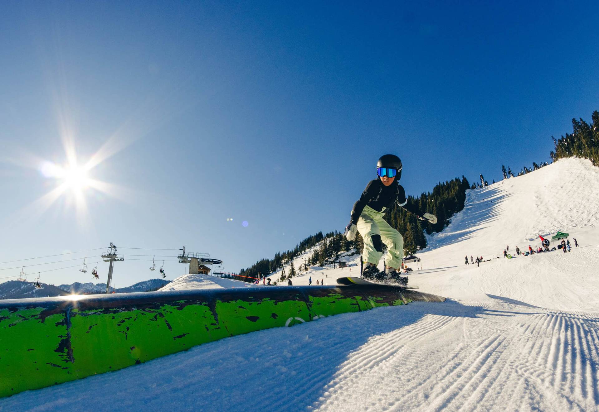 Youth snowboarder slides across a green tube in the greenhorn acres park