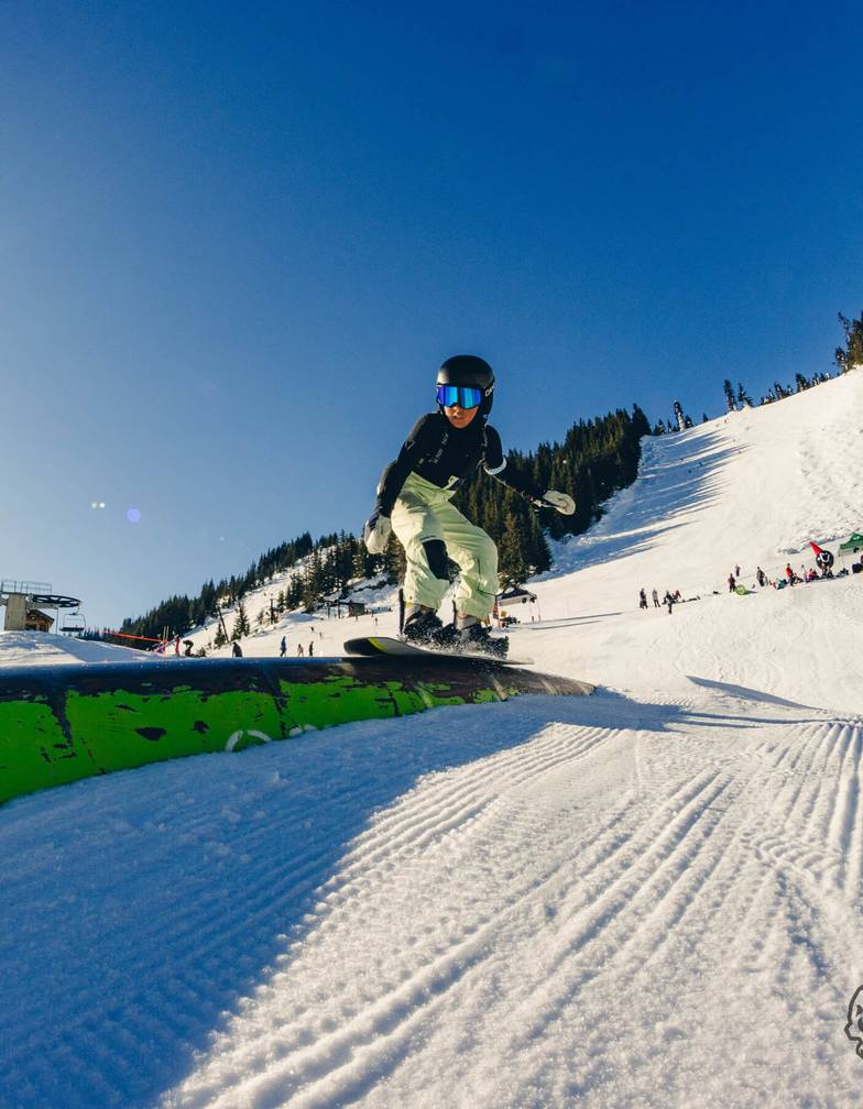 Youth snowboarder slides across a green tube in the greenhorn acres park