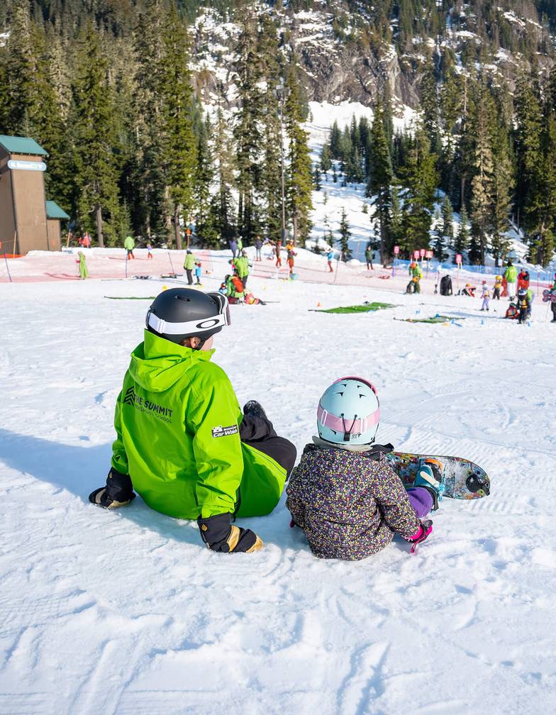instructor sitting with snowboard student