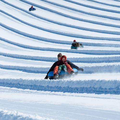 child sitting in parents lap riding tub down hill