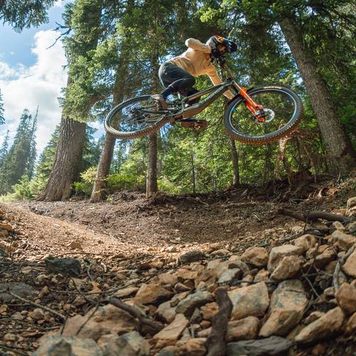 woman jumping a gap in the forest