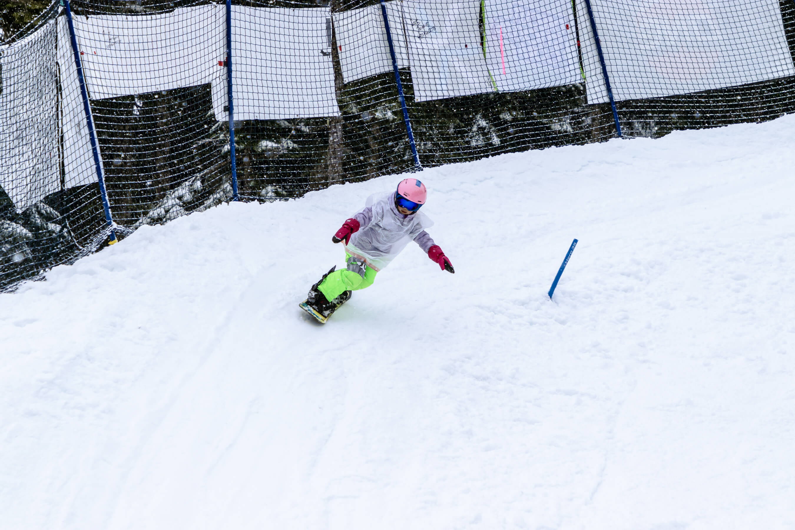 young racer in pink helmet rounds corner of banked slalom course