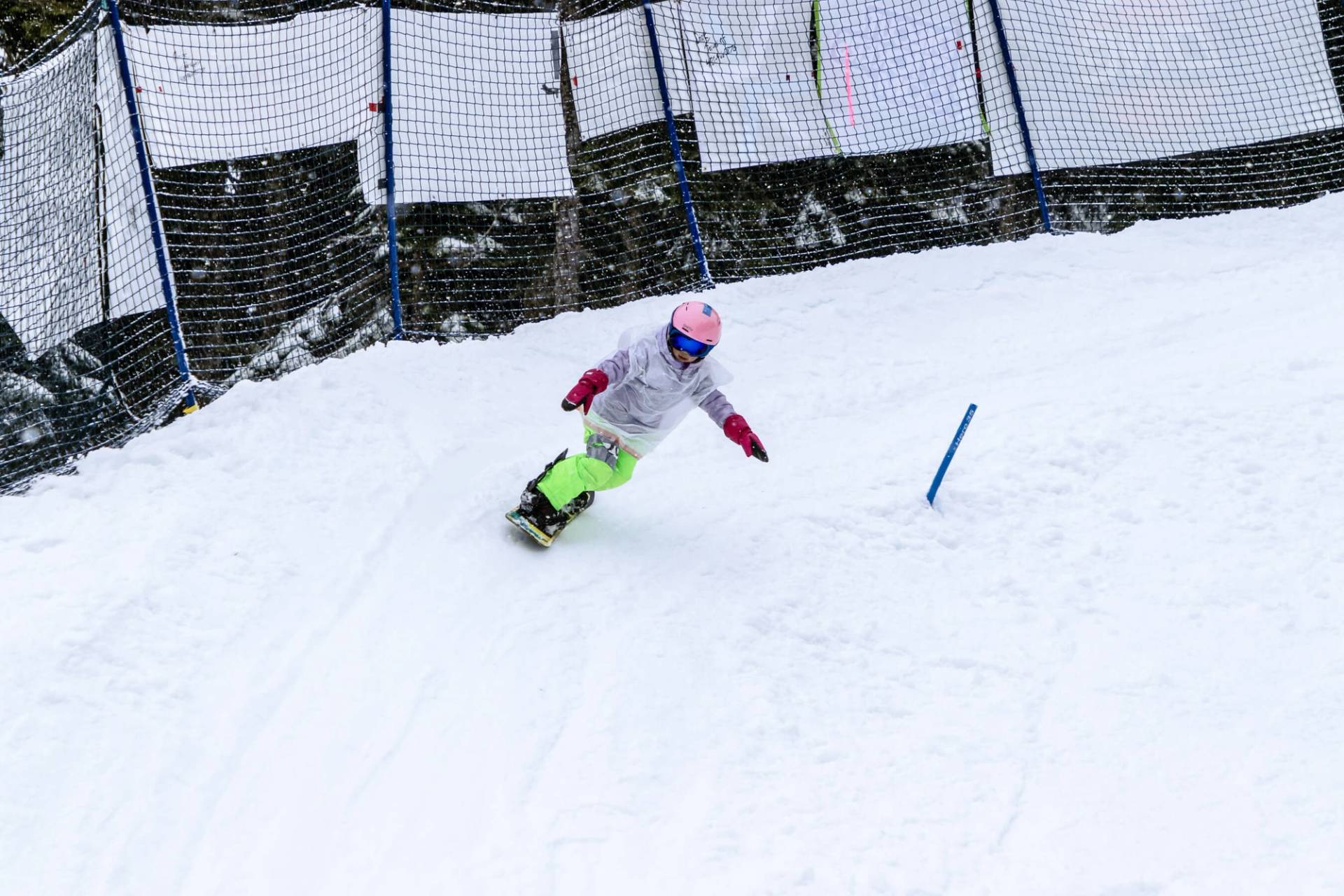 young racer in pink helmet rounds corner of banked slalom course