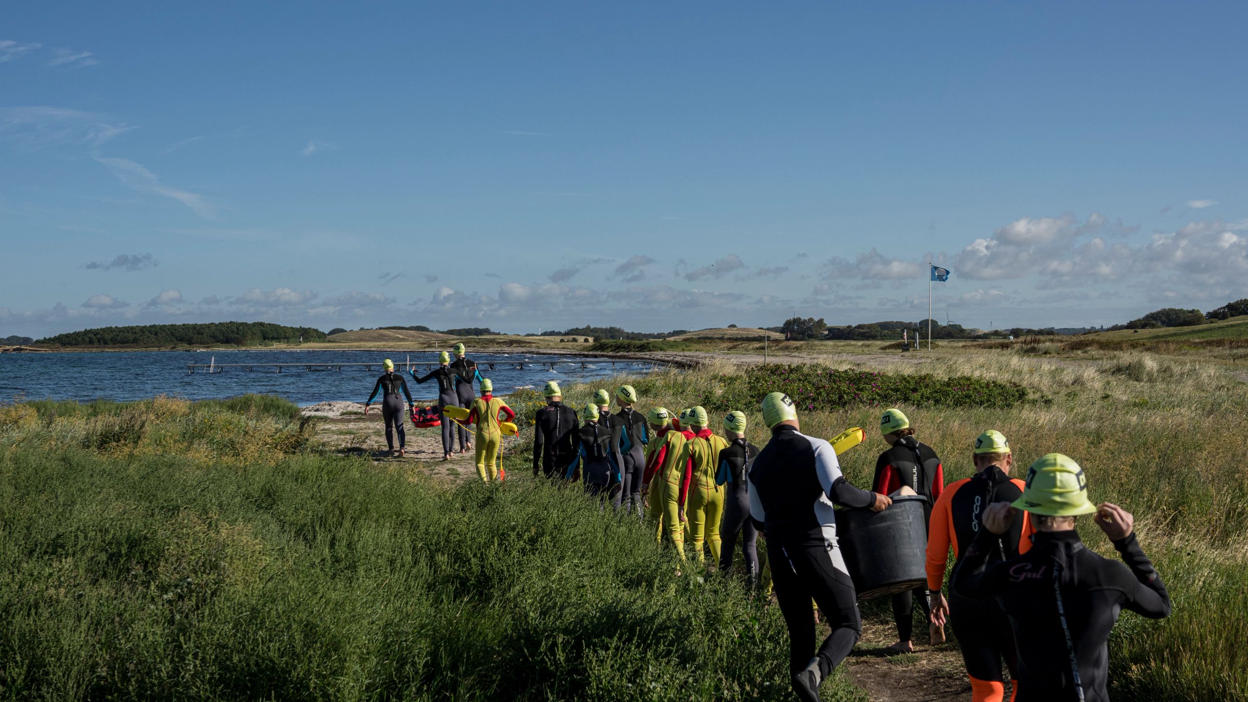 en gruppe mennesker i våddragter går mod vandet.