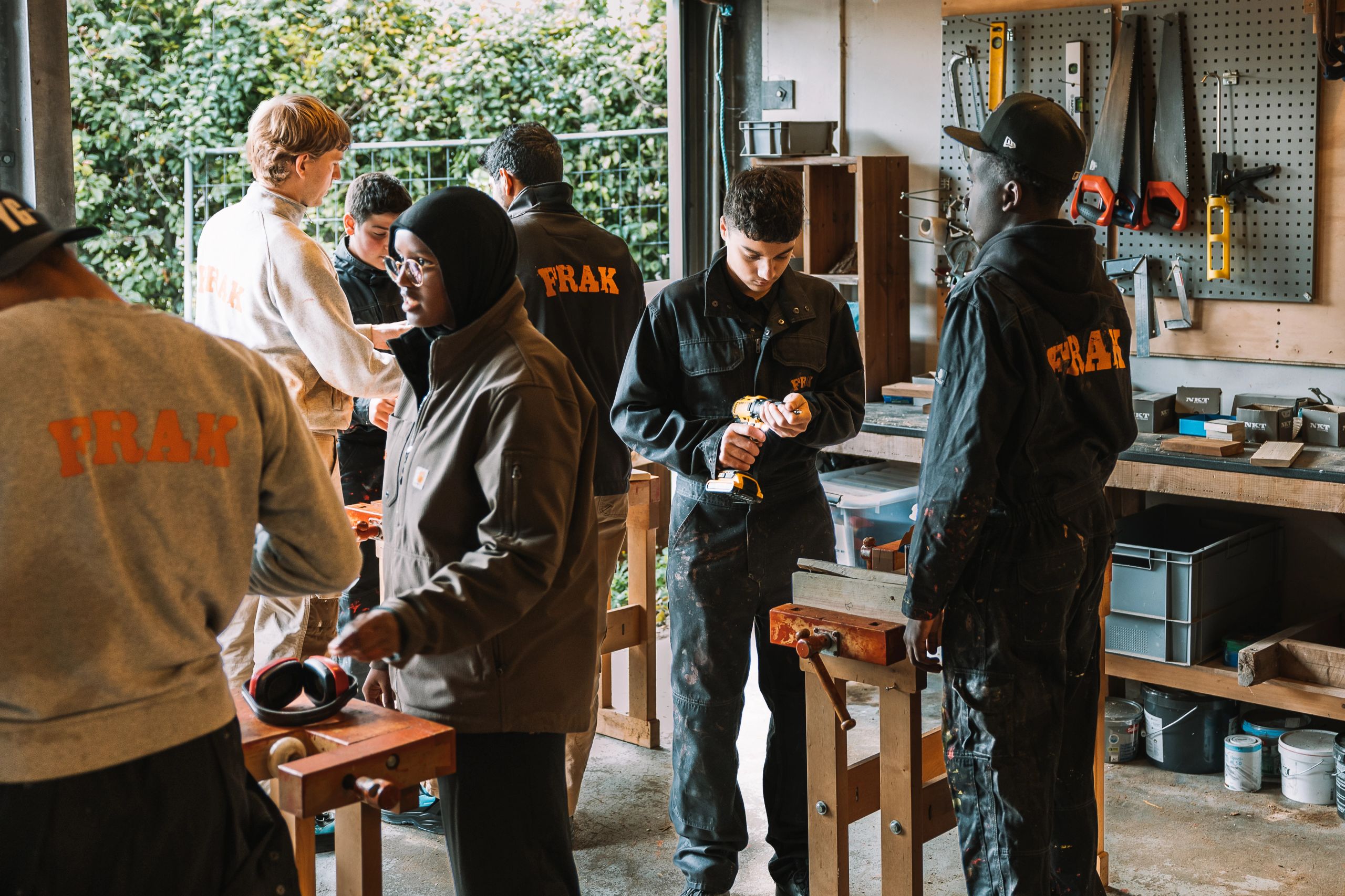 en gruppe mennesker står omkring et træbord i et værksted.