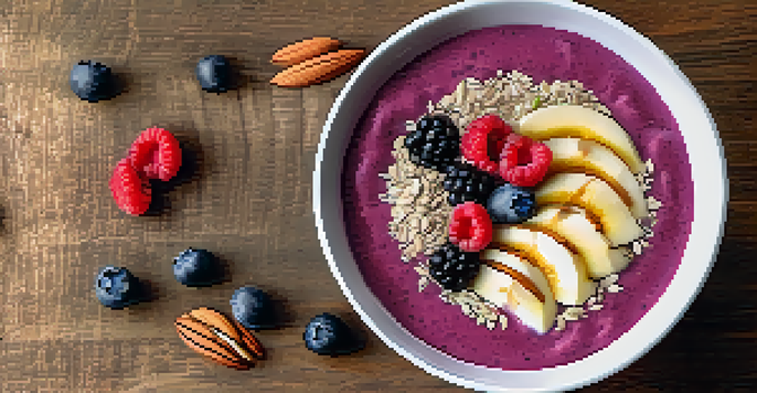 A colorful smoothie bowl with almond slices and chia seeds on top, placed on a wooden table.