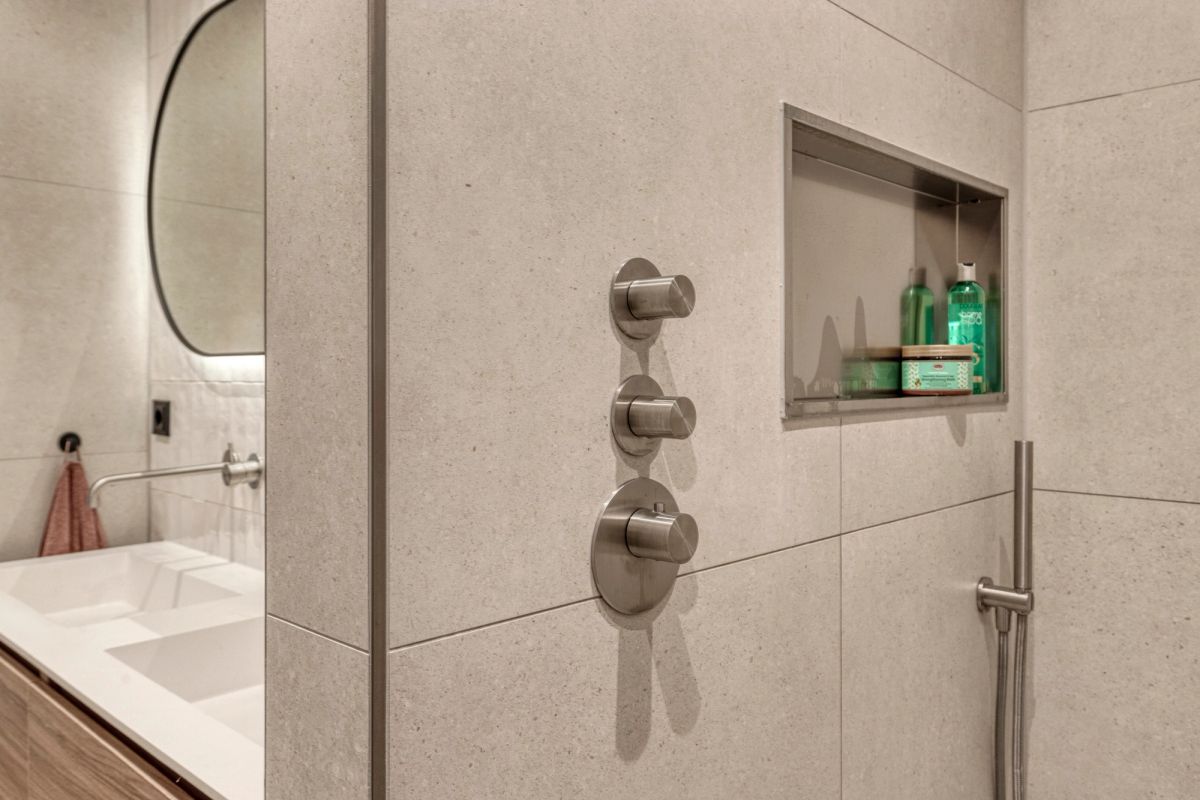 Detail van de geborsteld stalen inbouwkranen en thermostaat bij de douche