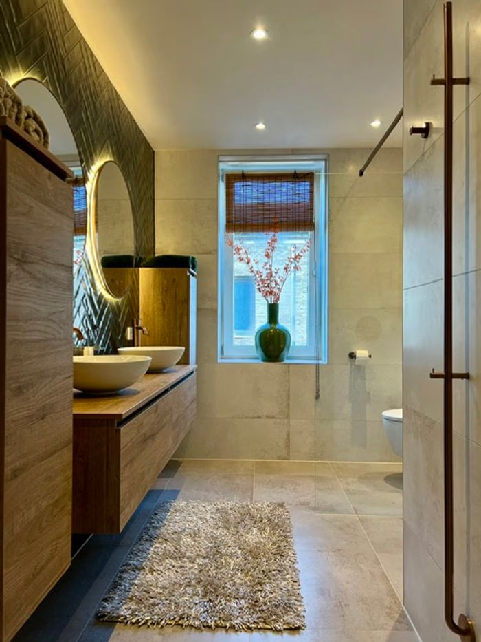 Luxe badkamer met zandkleurige tegels, houten meubel en koperkleurige kranen