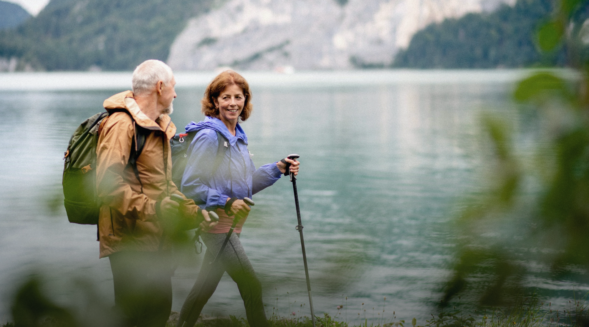 A middle aged man and woman hiking with walking sticks