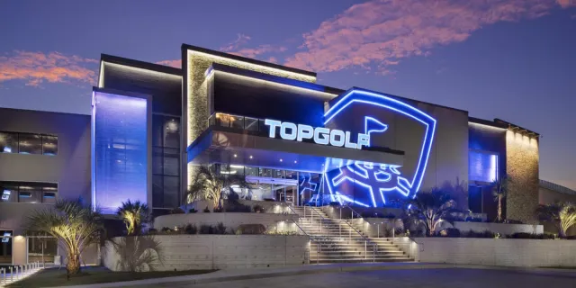 The illuminated Topgolf exterior at night.