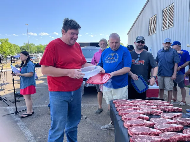 A volunteer carries packaged steaks from the selection table.