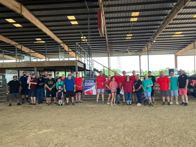 Gene Potts Memorial cookoff participants pose together inside the covered arena.