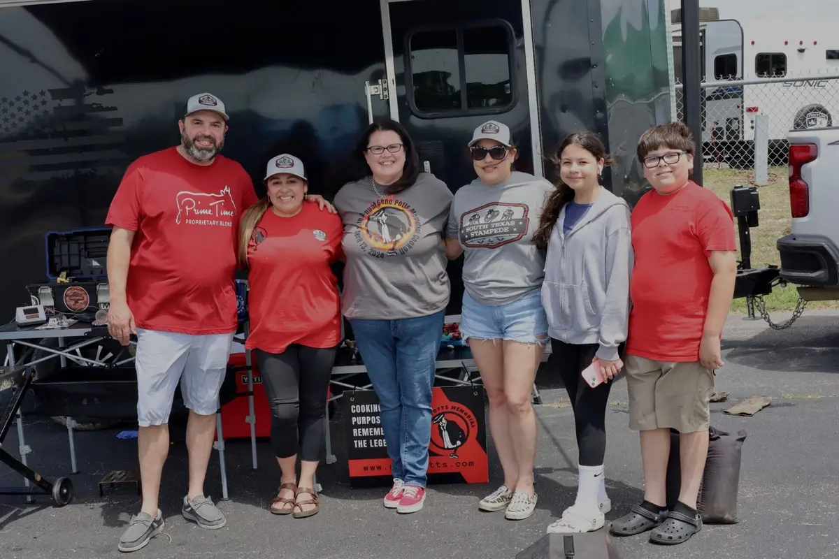 Six cooking team members pose together beside their trailer.