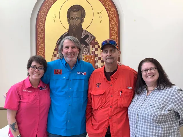 Four Gene Potts Memorial supporters pose together beneath a religious icon.