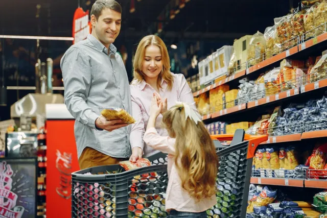 A family shops for groceries together with a Kroger cart.