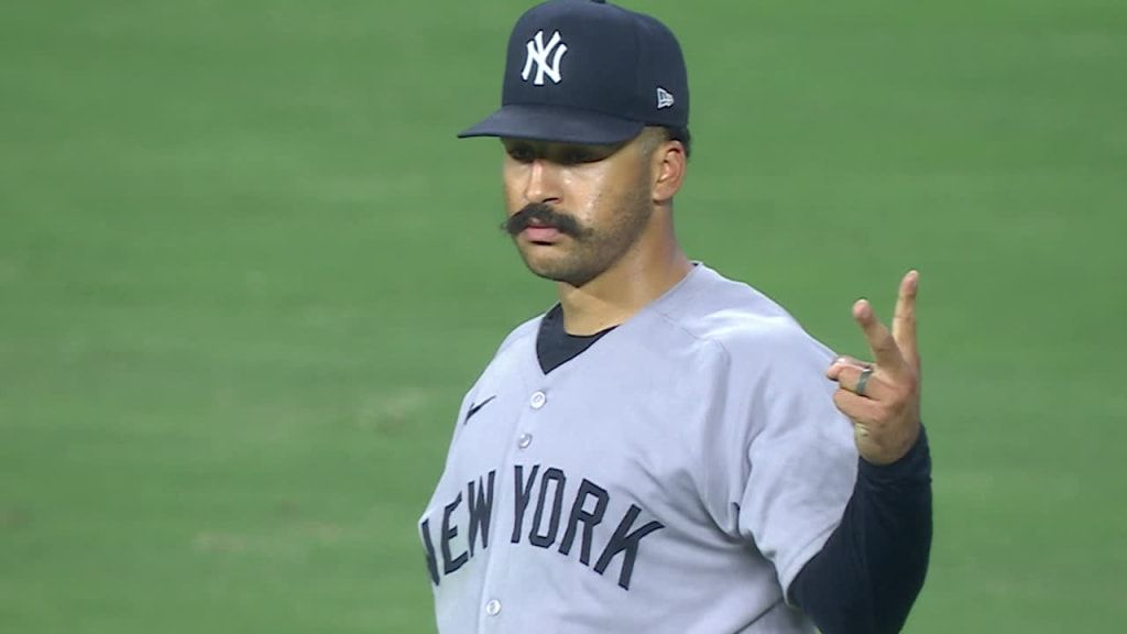 Trent Grisham tracks a fly ball in center field at Yankee Stadium as fans look on.