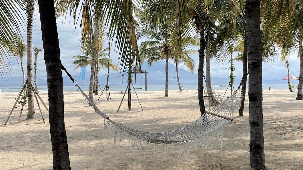 a woman is sitting in a lotus position on a wooden deck at sunset .