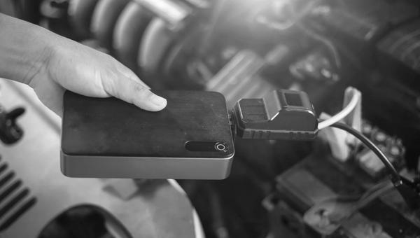 Portable car jump starter pack connected to a vehicle battery for emergency flat battery assistance