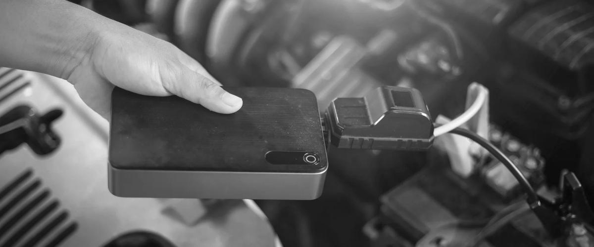 Portable car jump starter pack connected to a vehicle battery for emergency flat battery assistance