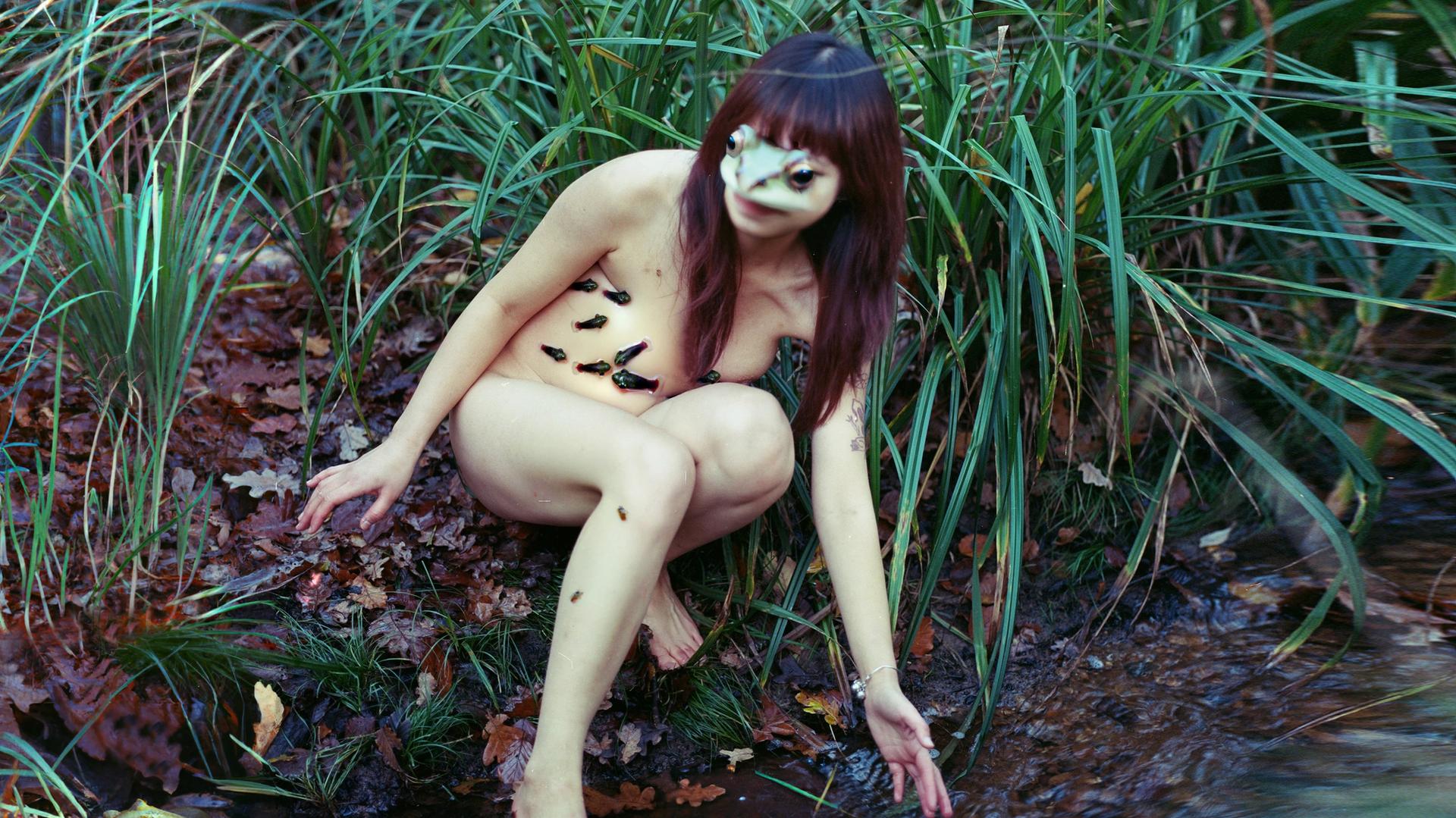 Photo of nude woman in grass with frog face superimposed on hers