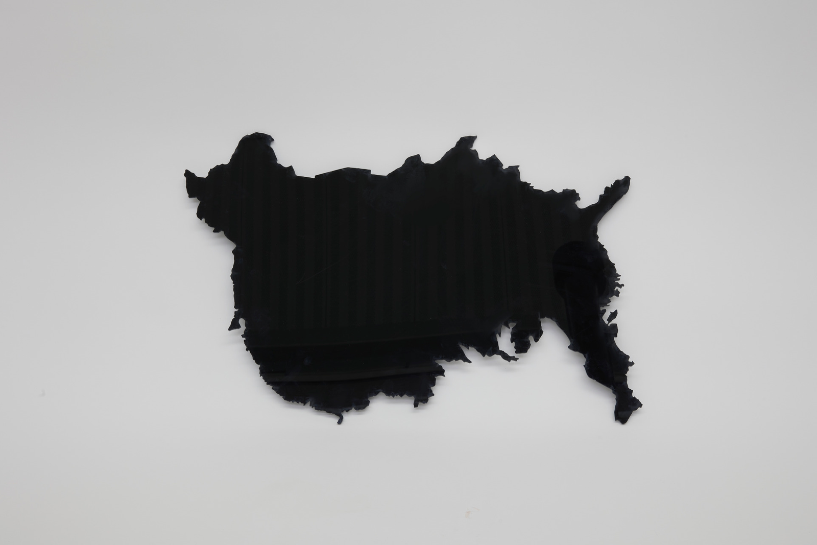 A black acrylic sheet cut in the shape of the China and USA maps overlapped to create an ambiguous shape.