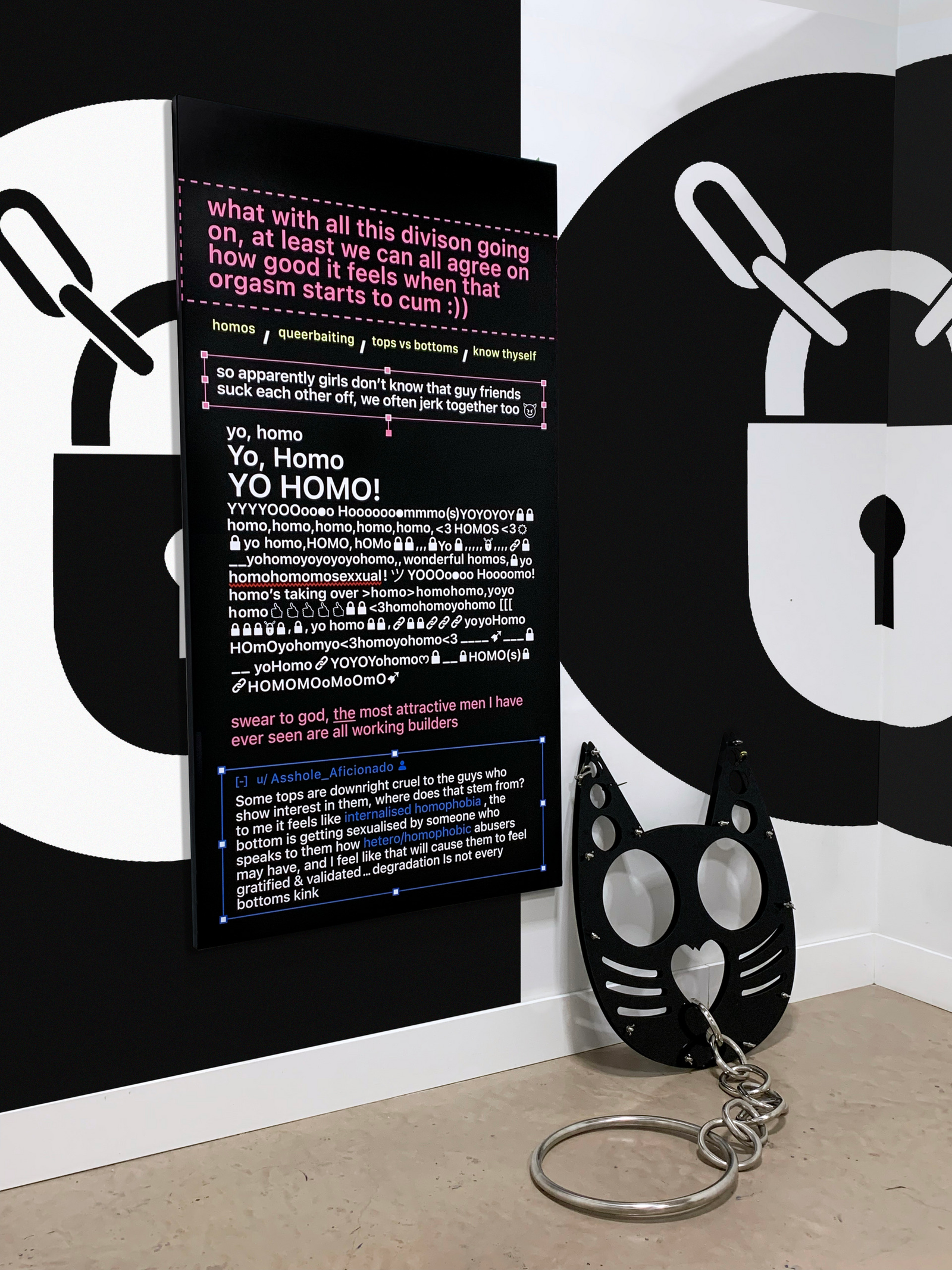 An image of an installation, hand painted graphic text and a enlarged cat knuckleduster made out of metal