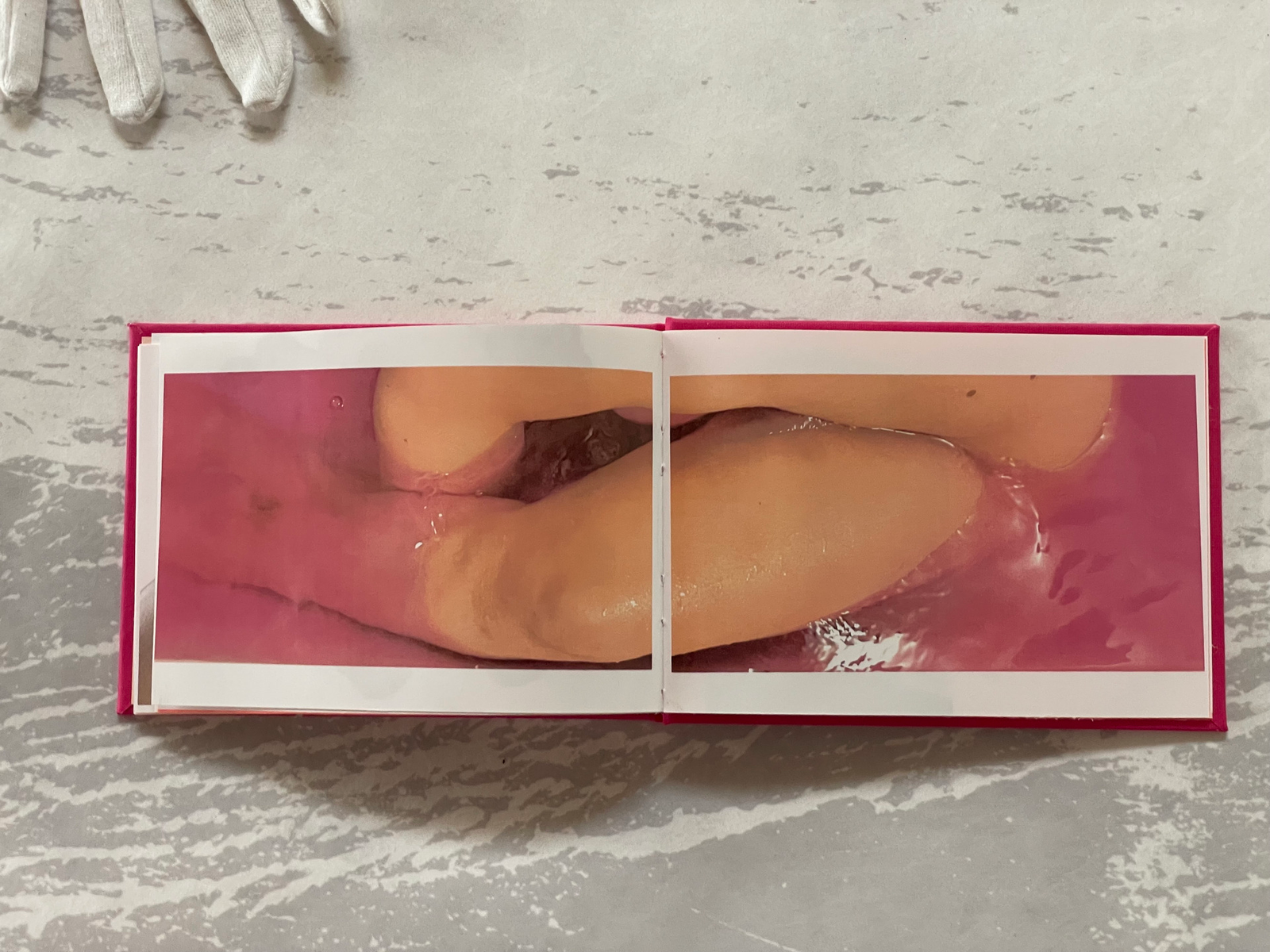 double page image of a cropped body in a bright pink liquid