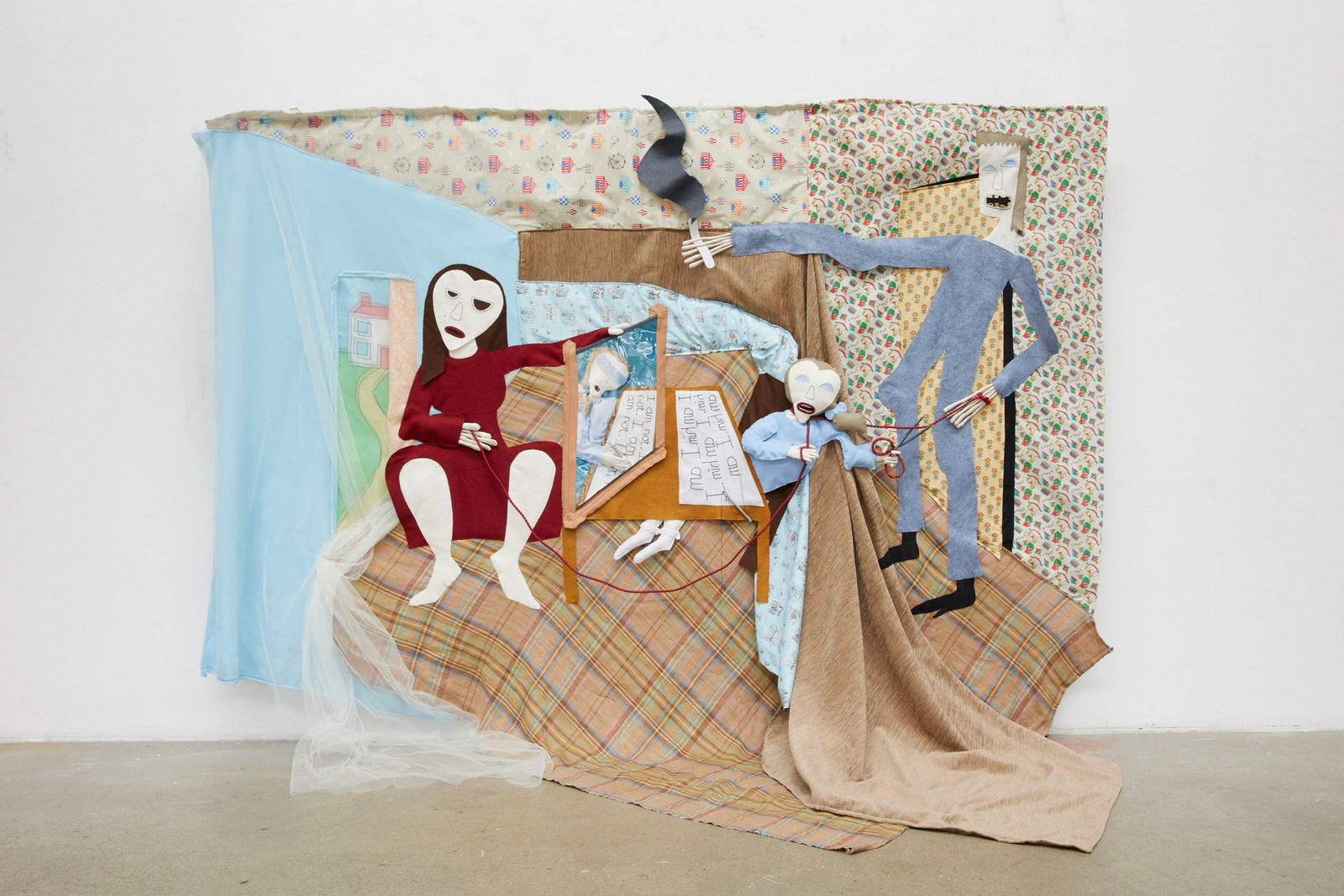 textile-based work hanging from a wall and depicting and adult male, adult female and female child in a distorted room