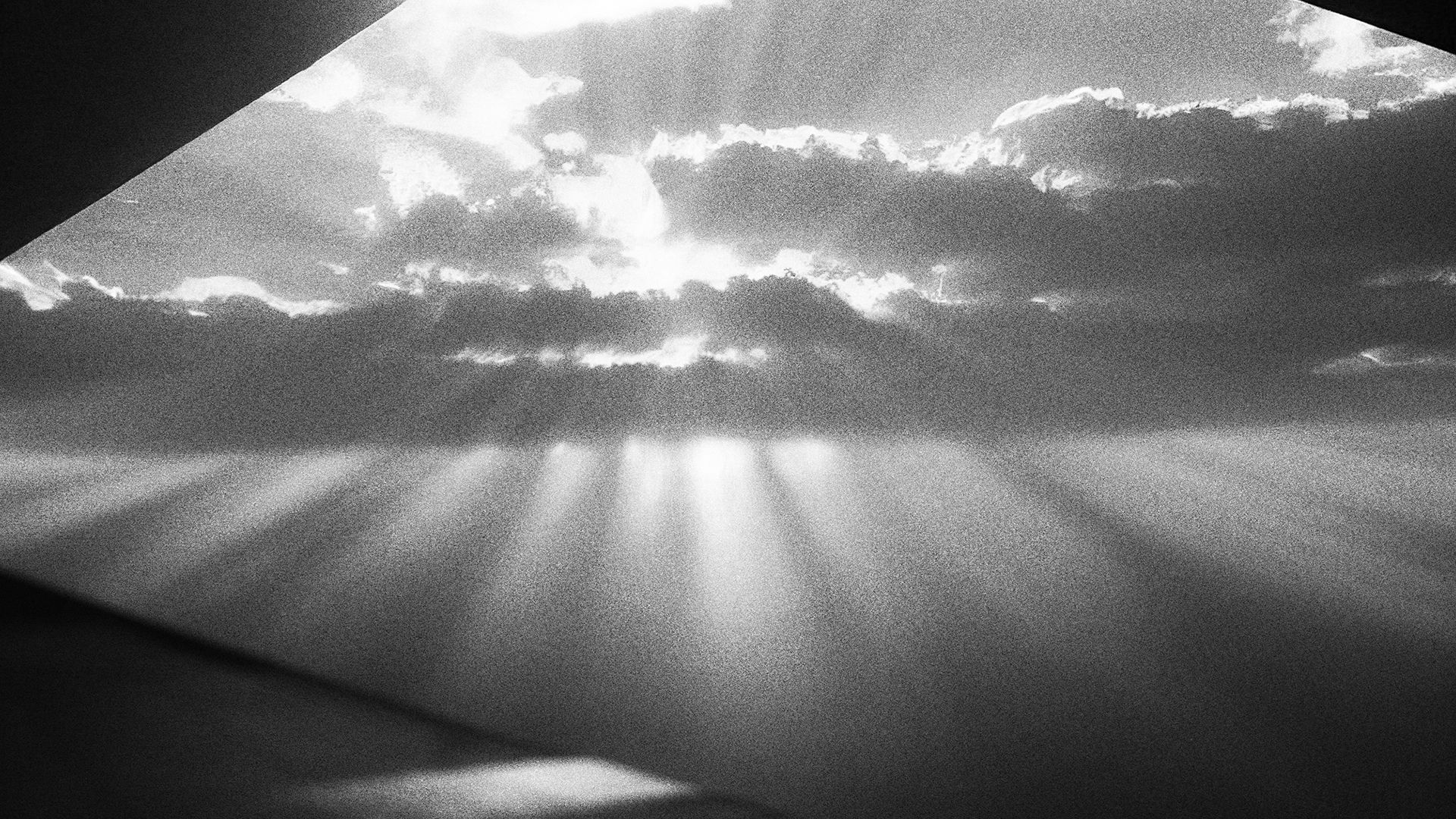 A black and white photo where a new world's sky is visible beyond the screen spread out like a movie theater, and light is shining.
