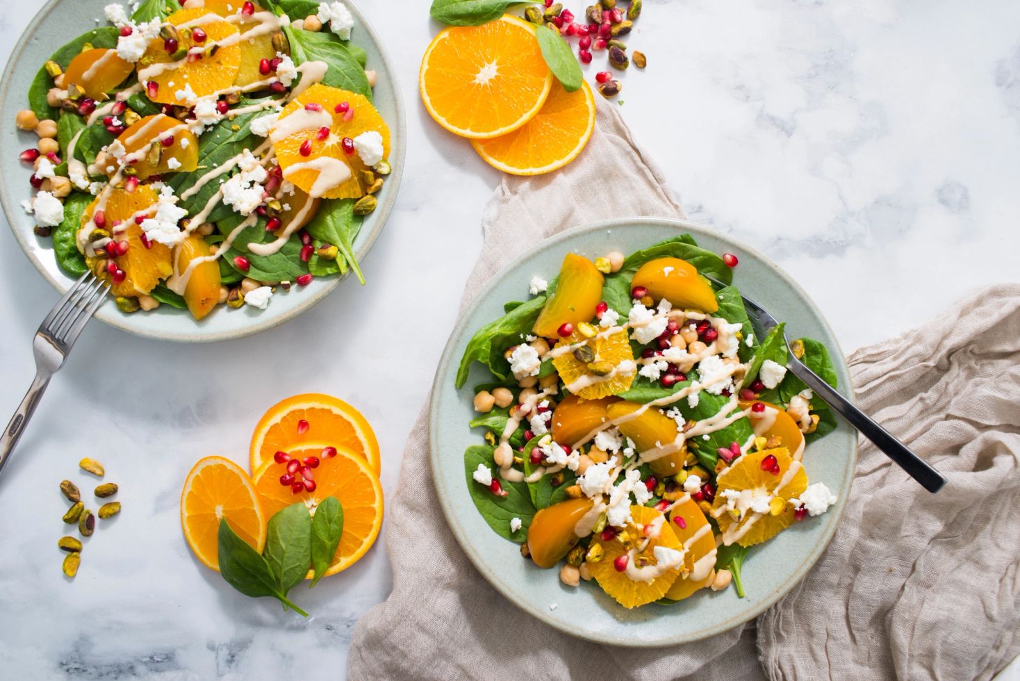 Citrus and feta winter salad with orange, pomegranate, chickpeas and pistachios on two plates