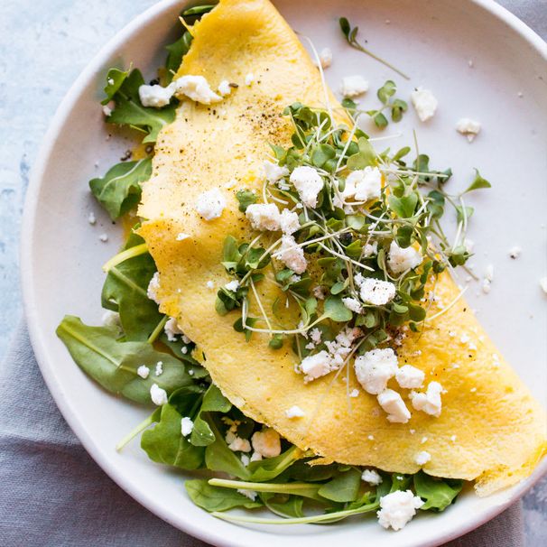 Feta and greens omelette folded over arugula and microgreens on a plate