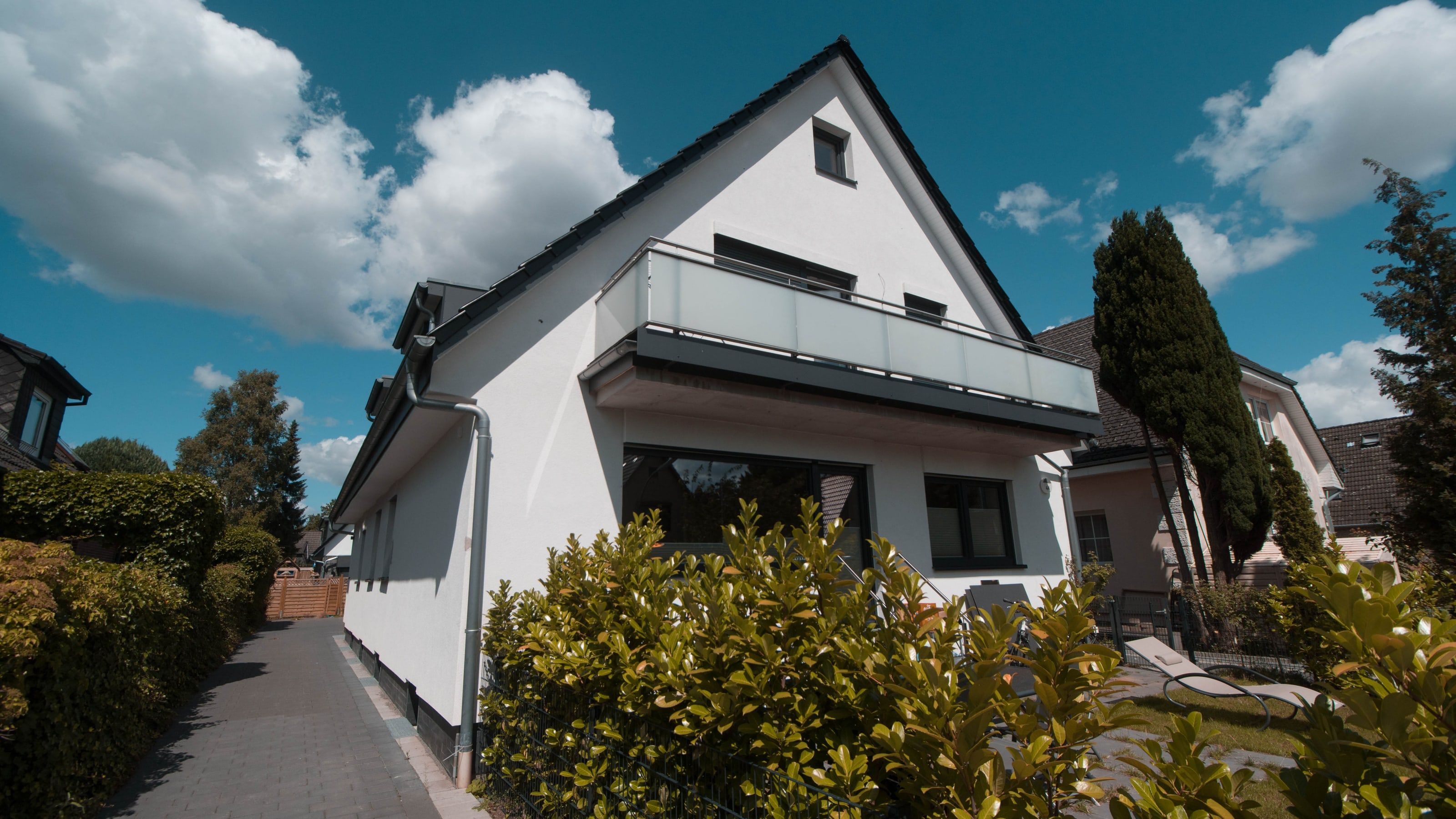 Weiß verputztes Mehrfamilienhaus mit Balkonen und Satteldach