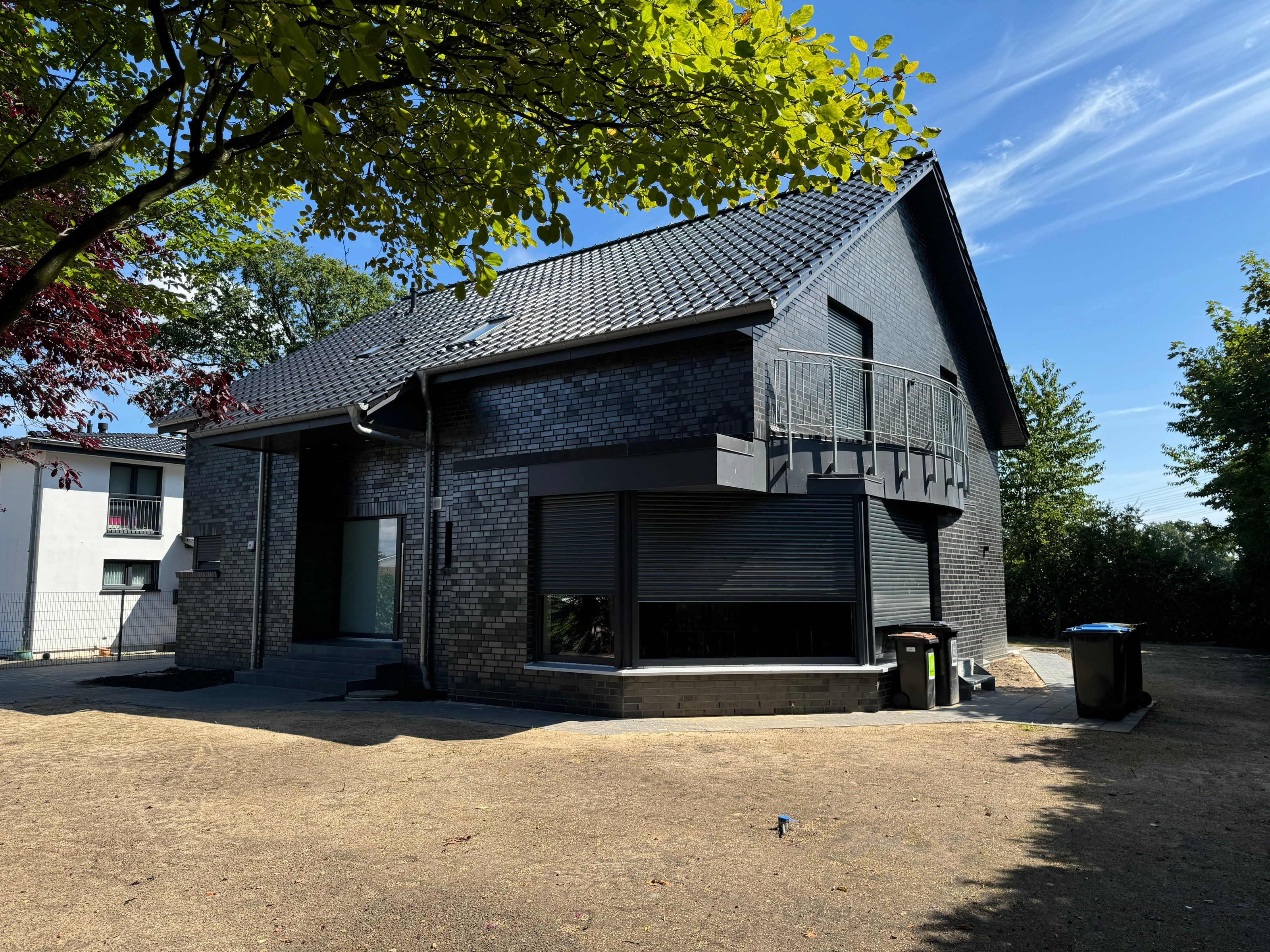Einfamilienhaus mit dunkler Klinkerfassade und Balkon über dem Eingang