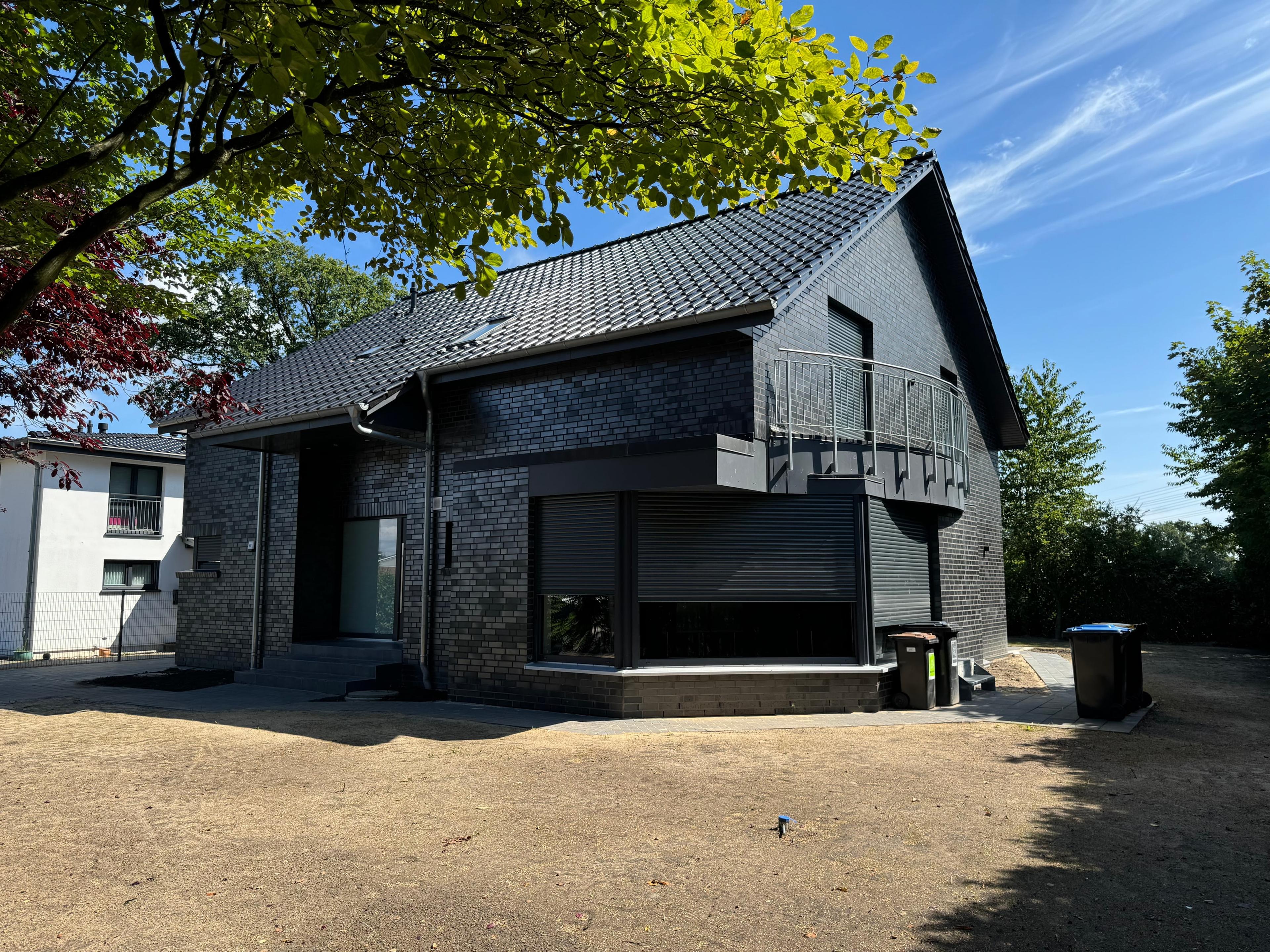 Einfamilienhaus mit dunkler Klinkerfassade und Balkon über dem Eingang