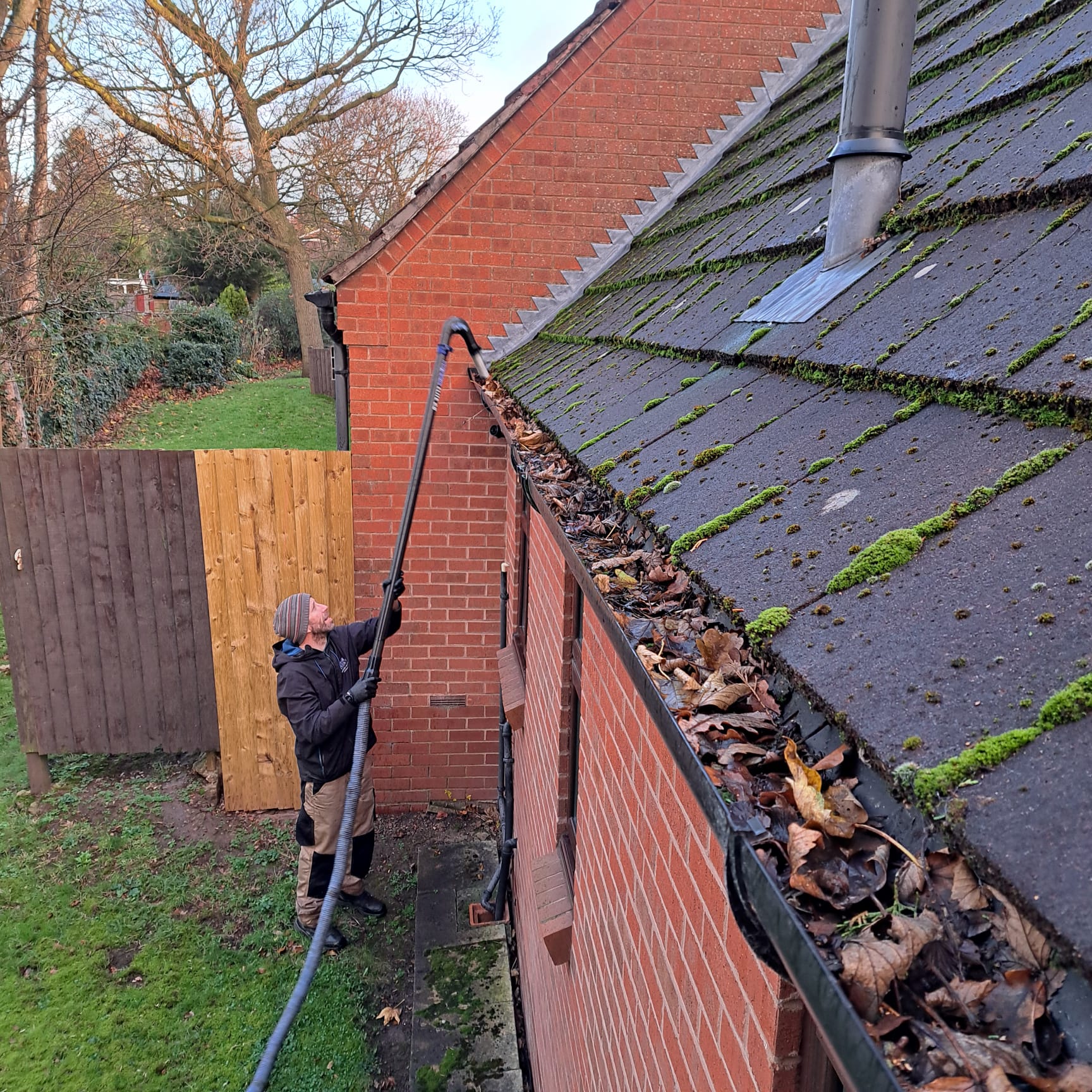 High-reach gutter vacuum clearing a blocked gutter