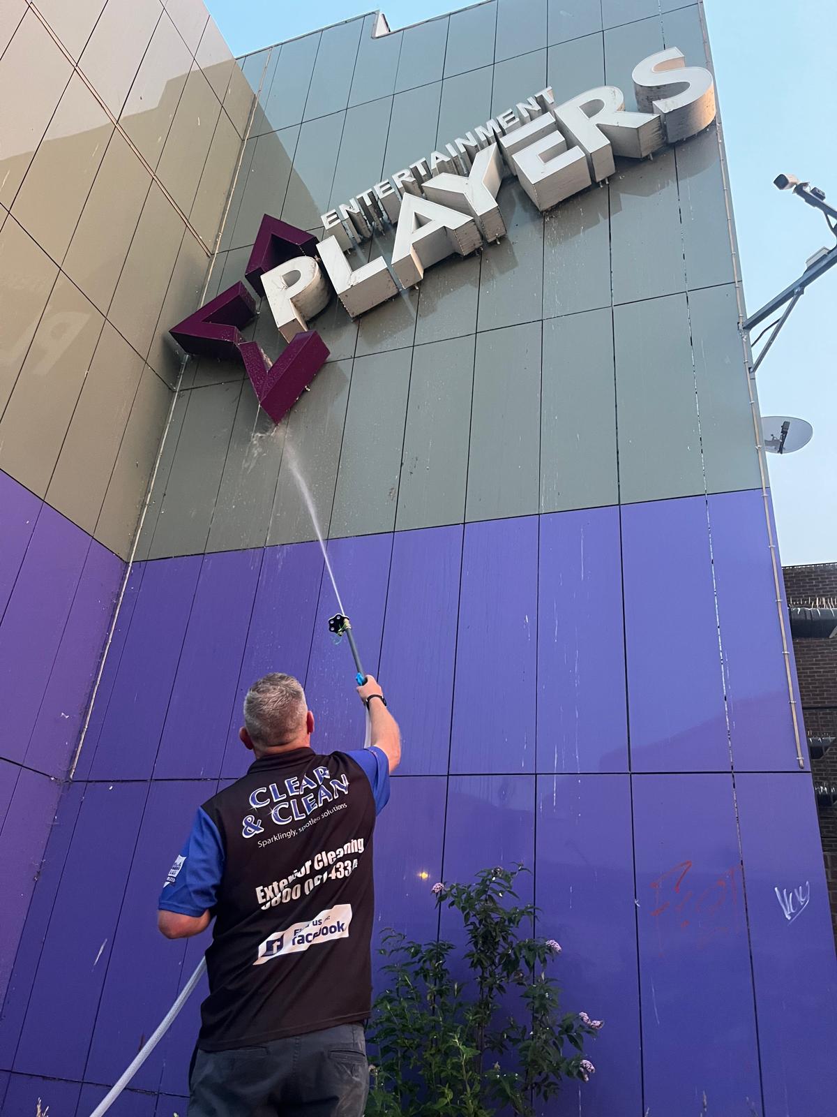 Low-pressure soft wash treatment being applied to a rendered wall