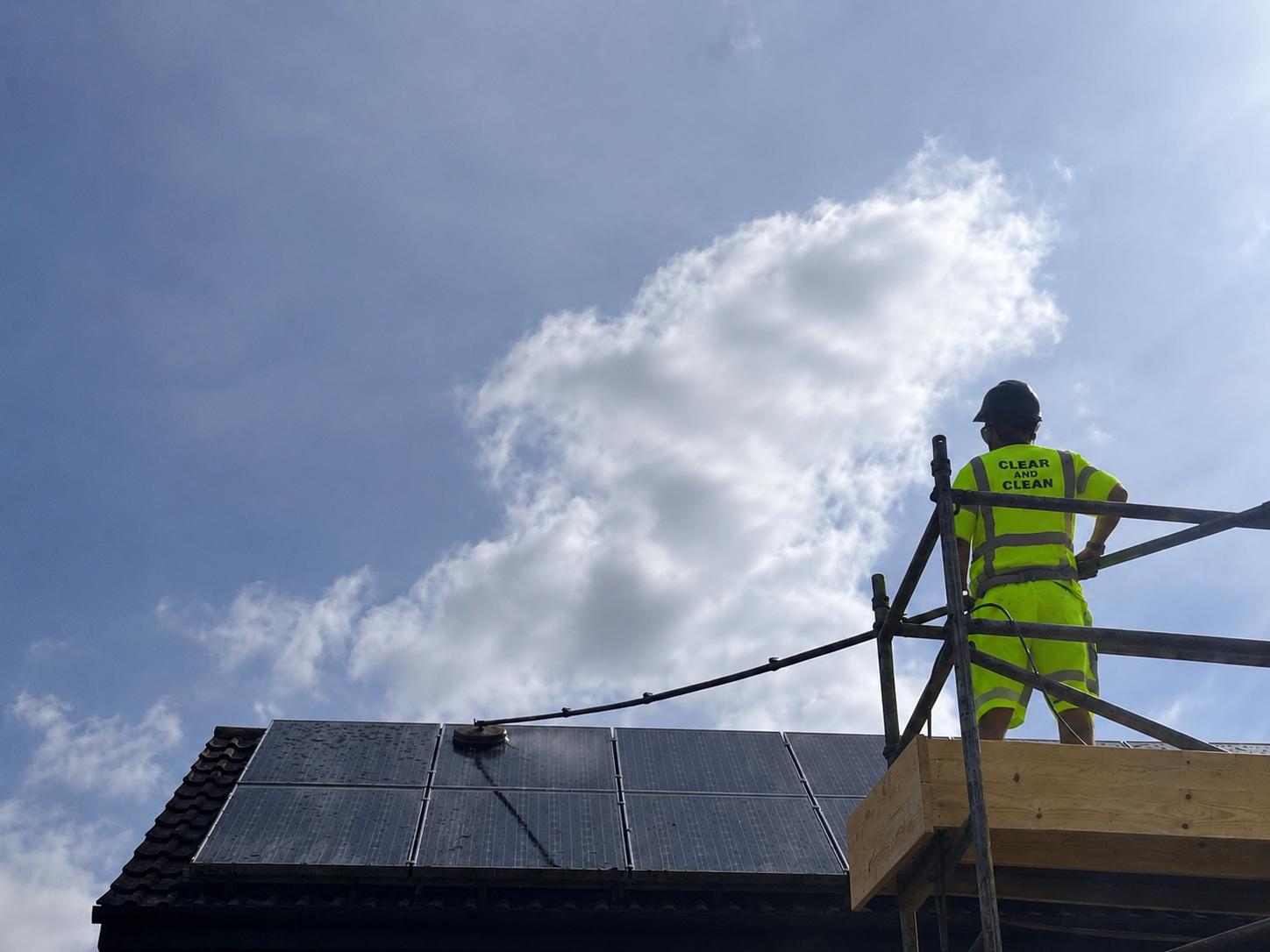 Operative cleaning a rooftop solar array in Clear & Clean workwear