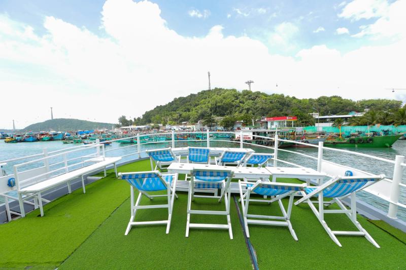 An empty open boat deck with reclining chairs, a table and railings