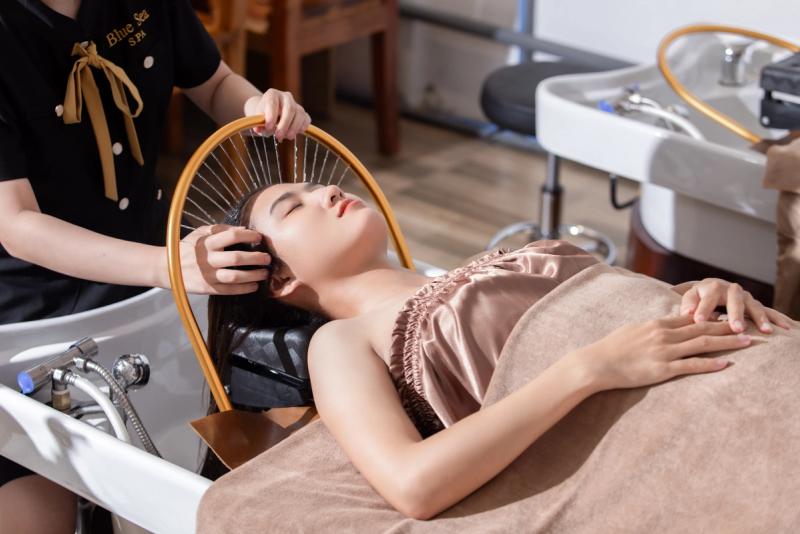 A therapist rinsing a guest’s hair at a wash basin