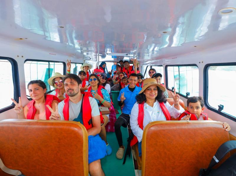 Passengers seated inside a boat cabin, several wearing red flotation vests