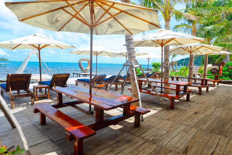 Wooden tables and umbrellas beside the sea at Dugong Beach Bar
